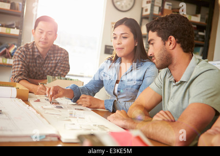 Three Architects Sitting Around Table Having Meeting Stock Photo