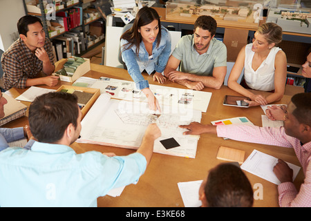 Female Boss Leading Meeting Of Architects Sitting At Table Stock Photo