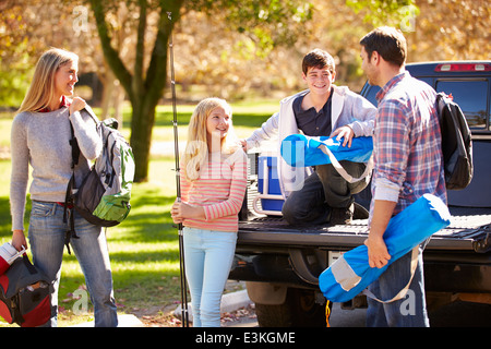 Family Unpacking Pick Up Truck On Camping Holiday Stock Photo