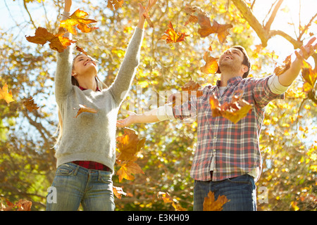 Couple Throwing Autumn Leaves In The Air Stock Photo