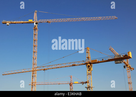 Several yellow tower cranes on a construction site Stock Photo