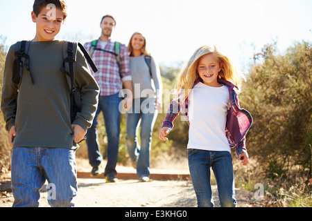 Mother And Children Hiking In Countryside Wearing Backpacks Stock Photo