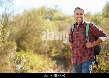 Portrait Of Man Hiking In Countryside Wearing Backpack Stock Photo