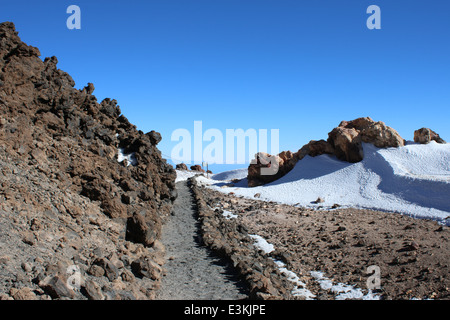 Hiking through snow at 3500m on the mountain peak of El Teide Volcano, highest summit on the Spanish Canary island of Tenerife Stock Photo