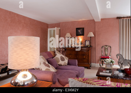 Purple sofa upholstered in Maya by Manuel Canovas in living room with marble topped French commode with drinks tray on top Stock Photo