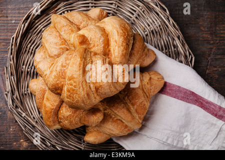 Croissants in wicker tray on dark wooden background Stock Photo