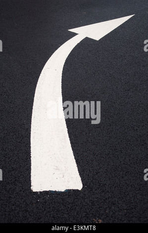 Curved white arrow painted on black tarmac. Stock Photo