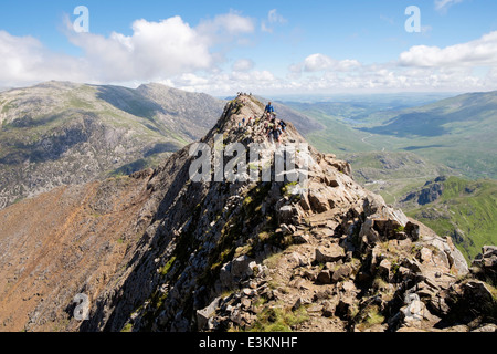 View back along red rocky Crib Goch ridge top scramble with hikers at start of Snowdon Horseshoe in mountains Snowdonia Wales UK Stock Photo