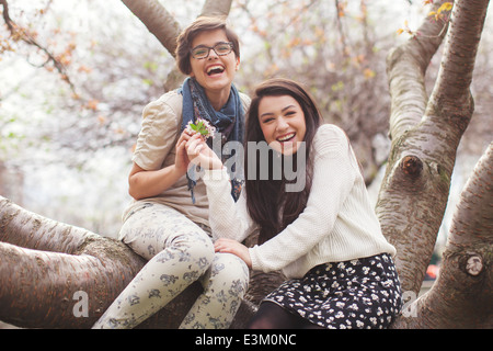 Portrait of two friends sitting on tree trunk, Massachusetts, USA Stock Photo
