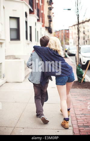 Rear view of young couple walking along city street Stock Photo