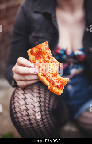Close up view of young woman's hand holding pizza Stock Photo