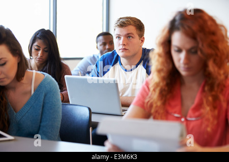 Male University Student Using Laptop In Classroom Stock Photo