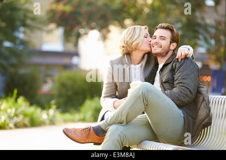 Couple Relaxing On Park Bench With Takeaway Coffee Stock Photo