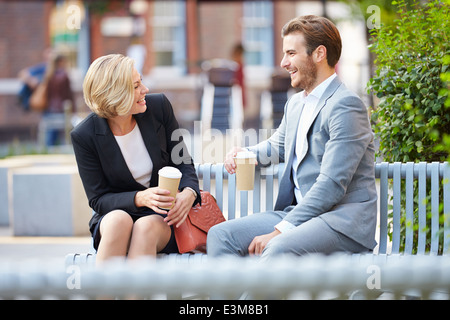 Business Couple On Park Bench With Coffee Stock Photo