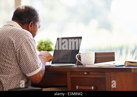 Senior Man Using Laptop On Desk At Home Stock Photo