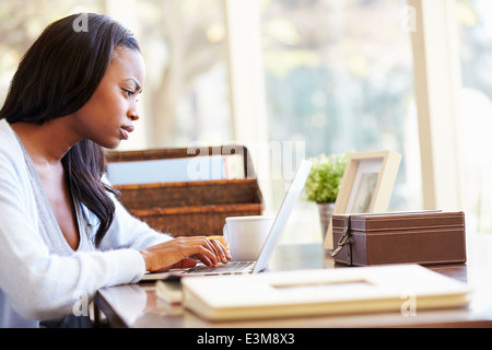 Woman Using Laptop On Desk At Home Stock Photo