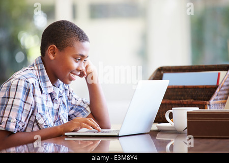 Boy Using Laptop On Desk At Home Stock Photo