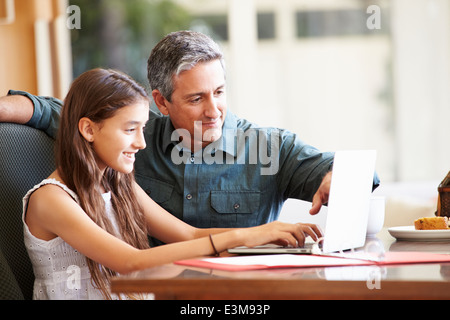 Father And Teenage Daughter Looking At Laptop Together Stock Photo