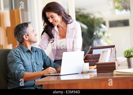Hispanic Couple Using Laptop On Desk At Home Stock Photo