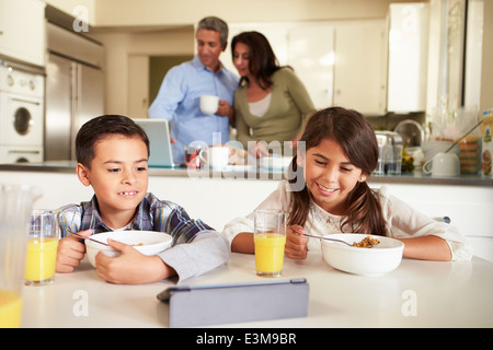 Hispanic Family Eating Breakfast Using Digital Devices Stock Photo