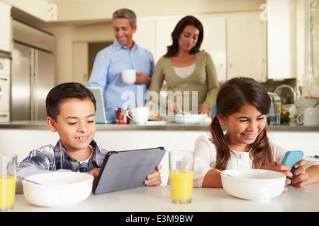 Hispanic Family Eating Breakfast Using Digital Devices Stock Photo