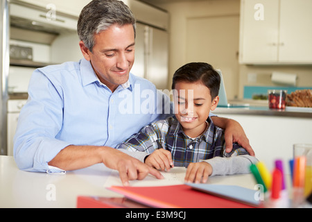 Hispanic Father Helping Son With Homework At Table Stock Photo