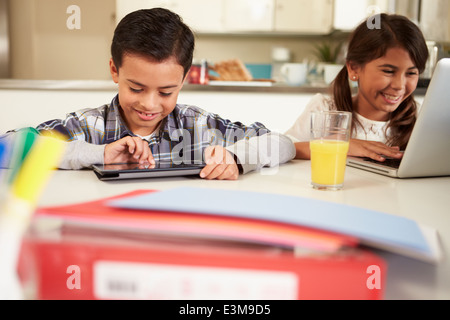 Children Using Laptop And Digital Tablet To Do Homework Stock Photo