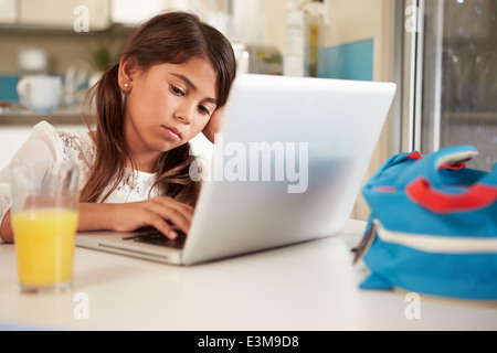 Unhappy Hispanic Girl Using Laptop To Do Homework At Table Stock Photo