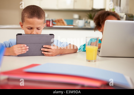 Children Using Laptop And Digital Tablet To Do Homework Stock Photo