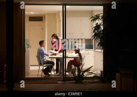 Family Eating Evening Meal Viewed From Outside Stock Photo