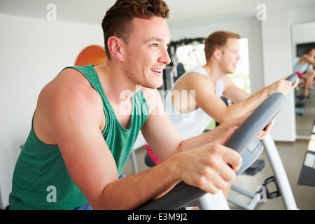 Two Young Men Training In Gym On Cycling Machines Together Stock Photo