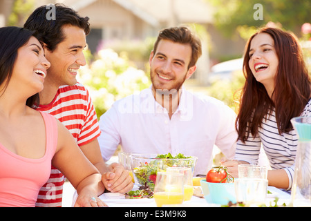Group Of Friends Enjoying Meal At Outdoor Party In Back Yard Stock Photo