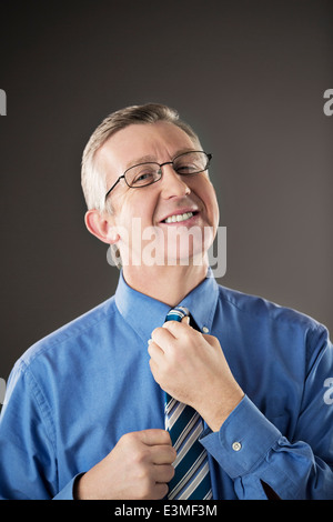 Portrait of businessman adjusting his tie Stock Photo
