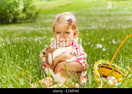 Small girl hugging rabbit in field Stock Photo