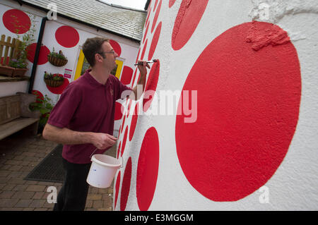 Langsett, North Yorkshire, UK. 25th June 2014. Cyclist, Rachel Goacher watches as Pete Sparks puts the finishing touches to his red polka dot cafe. It has taken Pete Sparks 40 hours to paint red polker dots all over his cafe beside the route of the Tour de France which starts in Leeds on July 5th. The tour will pass Bank View Cafe in Langsett, South Yorkshire on the second day's stage shortly after peloton has climbed to the highest point of the day in The Peak District. A red polker dot jersey will be worn by the rider who is first to the top. Credit:  Joanne Roberts/Alamy Live News Stock Photo