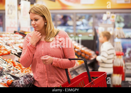 Thoughtful woman shopping vegetables in grocery store Stock Photo