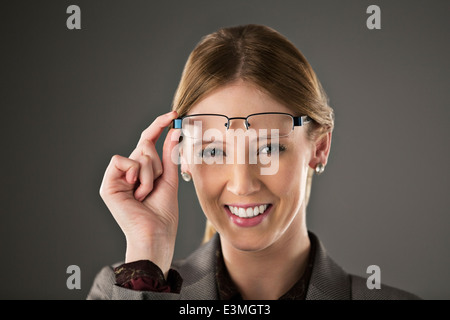 Portrait of confident businesswoman raising eyeglasses Stock Photo