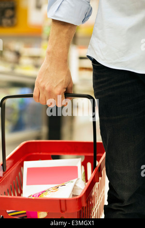 Cropped image of man carrying shopping basket in supermarket Stock Photo