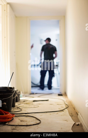 Rear view of carpenter standing at doorway in house under construction Stock Photo