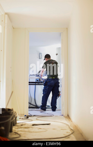 Full length rear view of carpenter working in house under construction Stock Photo