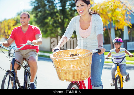 Happy family riding bikes on sunny street Stock Photo