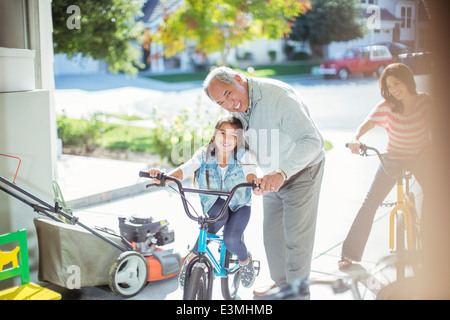 Grandfather and granddaughter on bike in garage Stock Photo
