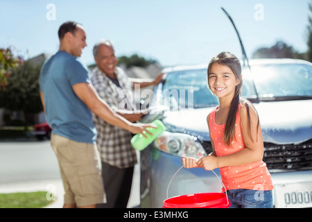 Multi-generation family washing car in sunny driveway