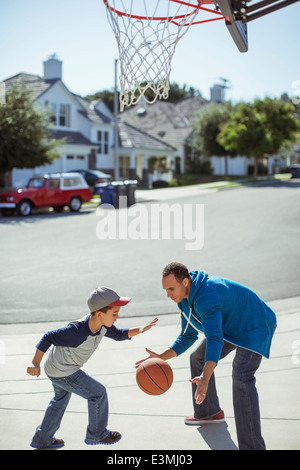 Father and son playing basketball in driveway