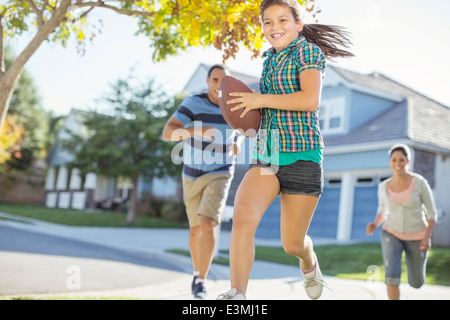 Family playing football in sunny street Stock Photo