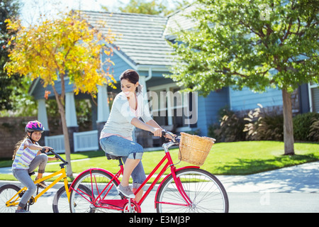 Mother and daughter riding bikes in street Stock Photo