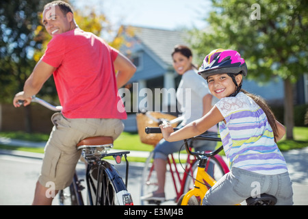 Portrait of family riding bikes on street Stock Photo