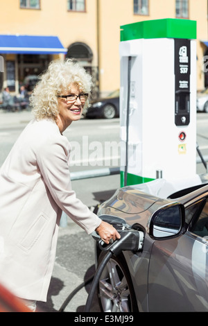 Smiling senior woman filling car with petrol at gas station Stock Photo