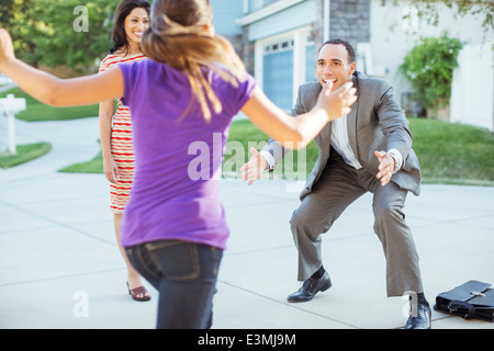 Daughter running to father in driveway Stock Photo