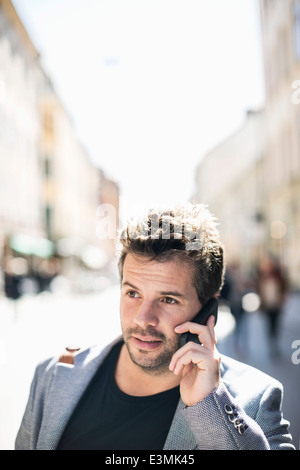 Mid adult businessman using smart phone on city street Stock Photo